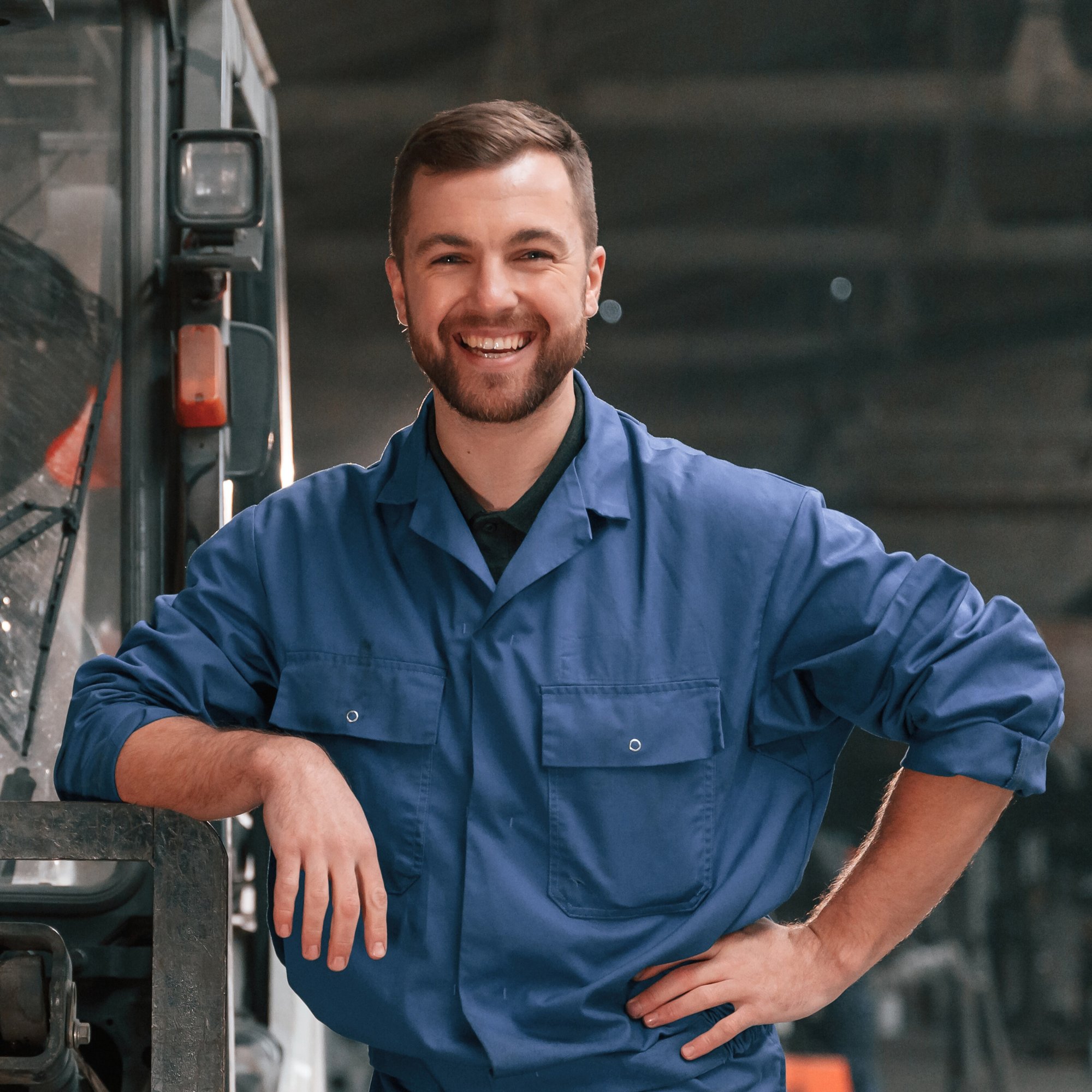 Leaning on the Forklift. Factory Worker in Blue Uniform Is Indoors - Edited